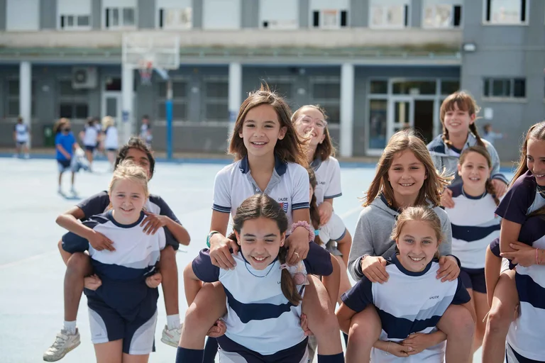 Students enjoy piggyback rides and play together in the school playground.
